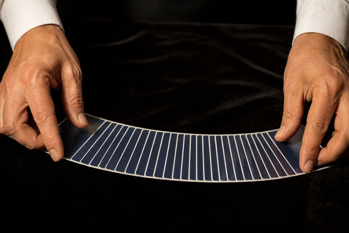 Mains d’un magicien étalant un jeu de cartes en ruban sur une nappe sombre